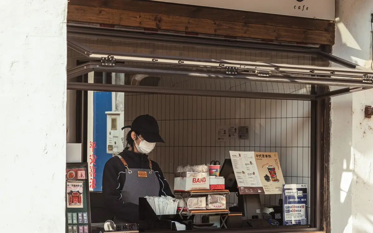 A small outdoor coffee kiosk counter with orders being prepared