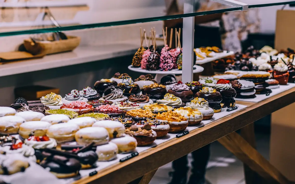 A display case of glazed and topped donuts and pastries