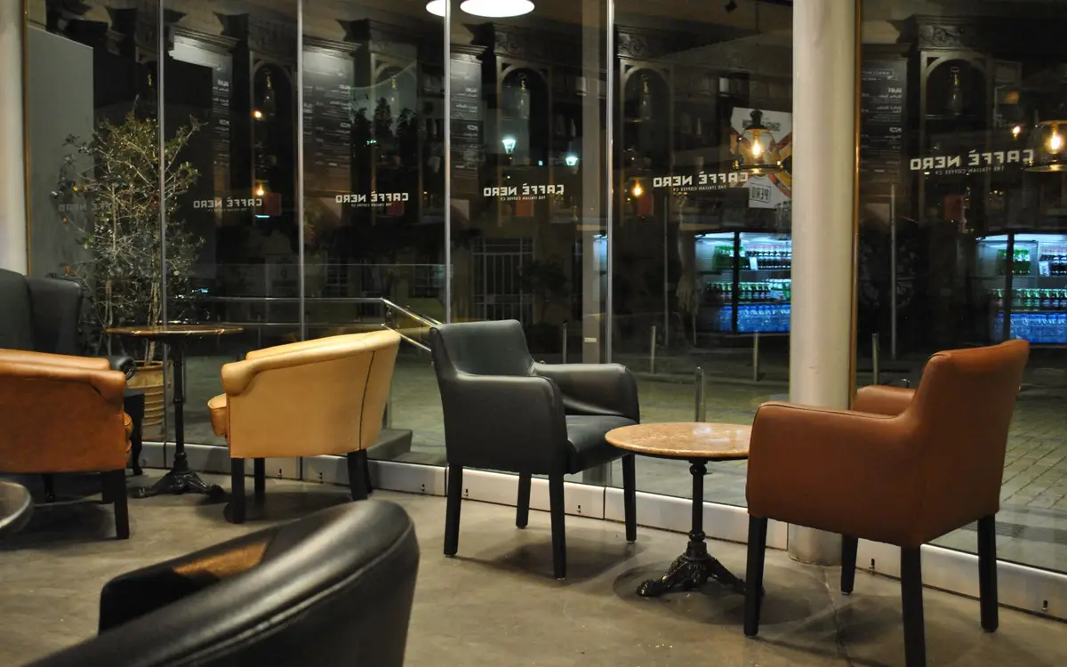 A quiet cafe seating area in the evening with large windows